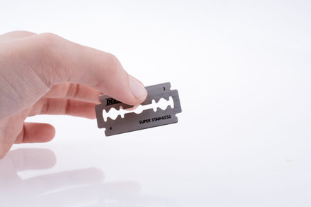 Hand holding a razor blade on a white background