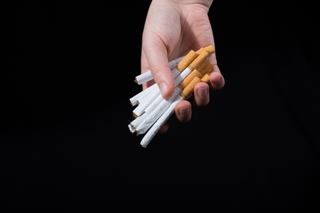 Hand is giving out bundle of cigarettes on black backgroundの写真素材