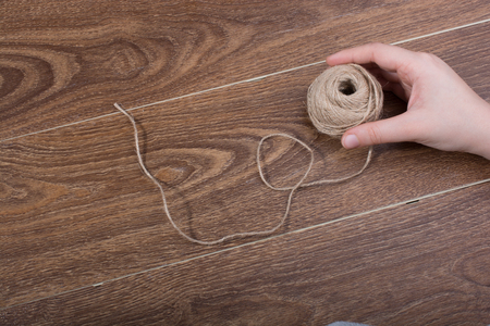 Spool of brown string in hand on  brown backgroundの写真素材