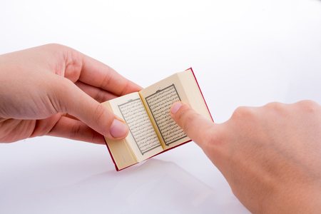 Hand holding The Holy Quran on a white backgroundの写真素材