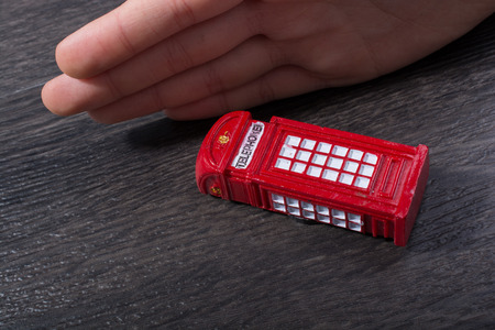 Hand holding a phone booth on a dark backgroundの写真素材