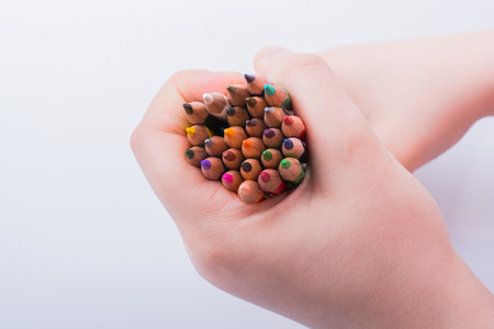 Hand holding color Pencils placed on a white backgroundの写真素材