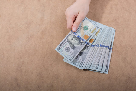 Hand holding American dollar  banknotes isolated on wooden background