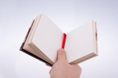 Hand holding a notebook on a white backgroundの写真素材