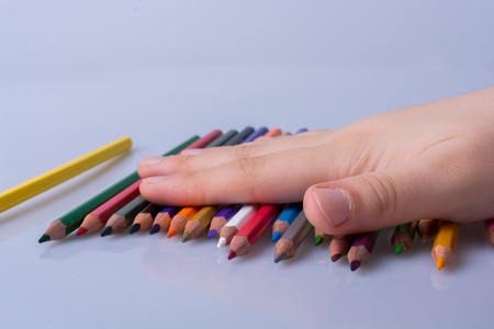 Hand holding color Pencils placed on a white backgroundの写真素材