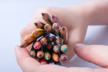 Hand holding color Pencils placed on a white backgroundの写真素材