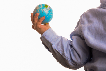Baby with blue shirt holding a small globe in hand on white backgroundの写真素材