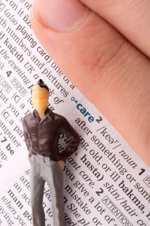 Hand holding a human figure on a newspaper by the word careの写真素材