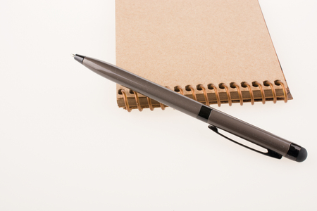 Spiral notebook and pollpoint pen on a white backgroundの写真素材