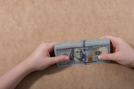 Hand holding American dollar  banknotes isolated on wooden backgroundの写真素材