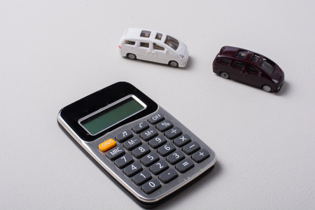 Little size cars beside a calculator on white backgroundの写真素材