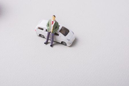 Tiny figurine of man before a miniature  carの写真素材