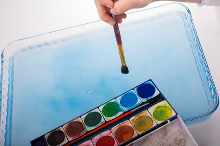 Paint dissolving in water as painting brush touching waterの写真素材