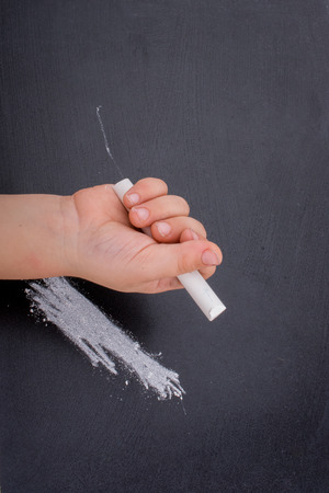 Hand holding  white chalk and black boardの写真素材