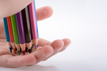 Hand holding color pencils on a white backgroundの写真素材