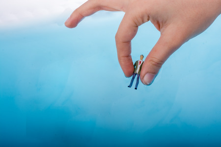 Hand holding a model airplane and a man figurine in blue waterの写真素材