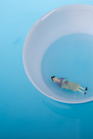 Little model globe with  figurine  floating in blue waterの写真素材