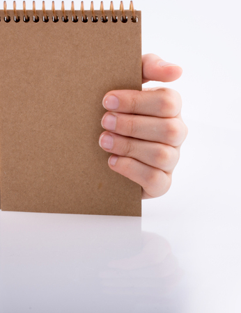Hand holding brown color notebook  on a white backgroundの写真素材