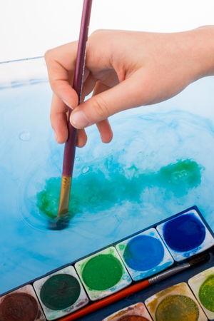 Paint dissolving in water as painting brush touching waterの写真素材
