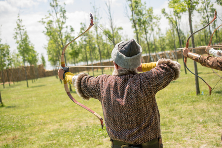 Archer with bow  in traditional clothes shooting an arrowの写真素材