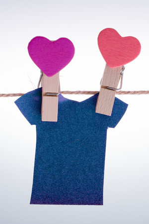 Paper clothes hang on a rope with the help of clothespinsの写真素材