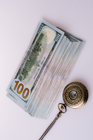 American dollar banknotes by the side of a watch on white backgroundの写真素材