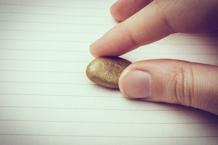 Little gold color pebble in the handの写真素材