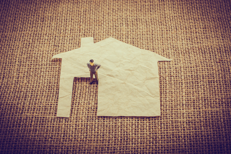 Man figurine and a house shape cut out of paperの写真素材