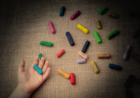 Used  color crayons and a toddlers hand holding oneの写真素材