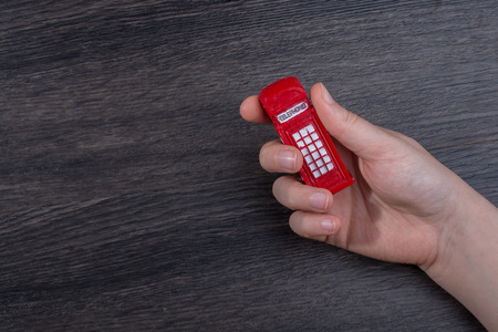 Hand holding a phone booth on a dark backgroundの写真素材
