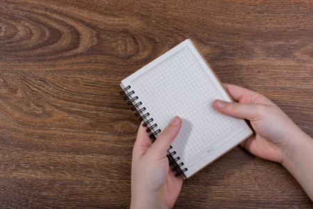 White notebook in hand on  a brown color background