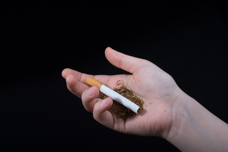 Hand is holding a cigarette on black backgroundの写真素材