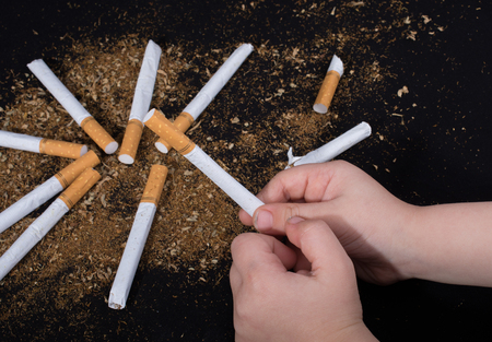 Hand is holding a cigarette on black backgroundの写真素材