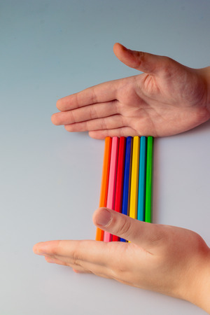 Hand holding color Pencils placed on a white backgroundの写真素材