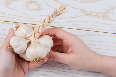 Hand holding cloves of garlic on a wooden textureの写真素材