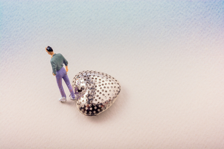 Tiny figurine of man with attached to a heart iconの写真素材