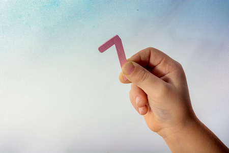 Number 7 seven  made of wood in the hand of a toddlerの写真素材