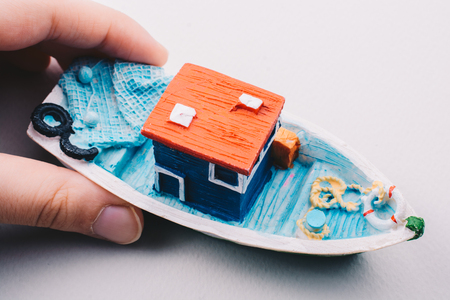 Little colorful model fishing boat in hand on whiteの写真素材
