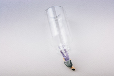 Tiny figurine of man miniature model coming out of bottleの写真素材