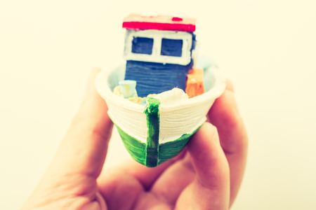 Little colorful model fishing boat in hand on whiteの写真素材