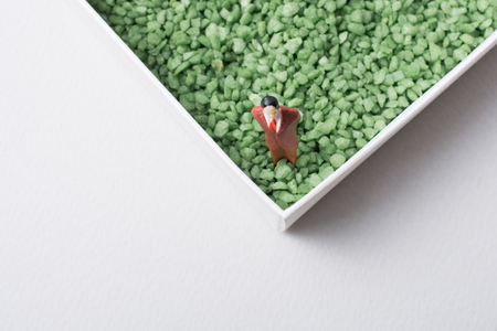 Tiny figurine of man miniature in green sand textureの写真素材