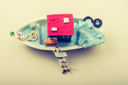 Tiny wrapped figurine of man model beside a model boatの写真素材