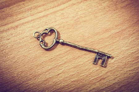 Retro styled decorative key placed on wooden textureの写真素材