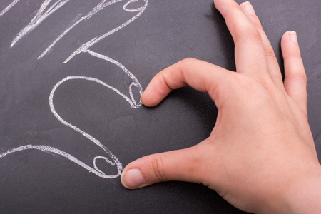Hands forming a heart on a blackboardの写真素材