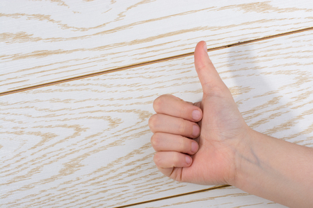 Hand making a thumbs up on a wooden backgroundの写真素材