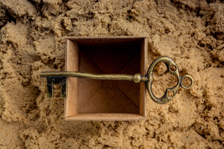 Retro style key placed in a brown box on sandの写真素材