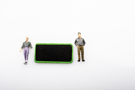 Two figurine by a black noticeboard on a whiteの写真素材