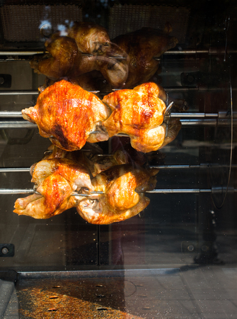 Chickens being grilled on metal spin in the viewの写真素材