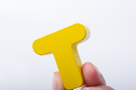 Hand holding letter cube T of made of woodの写真素材