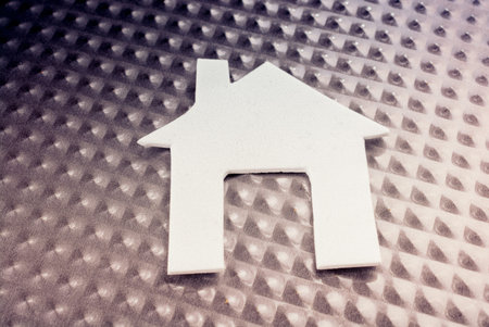 Little white paper house placed on metal backgroundの写真素材